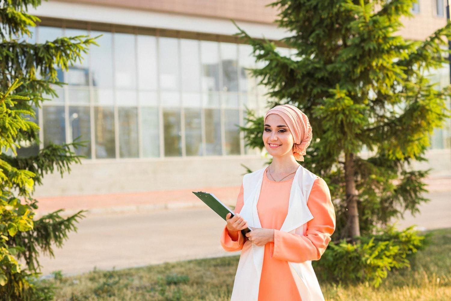 Female applicant with a clipboard standing near a university campus building in the UAE