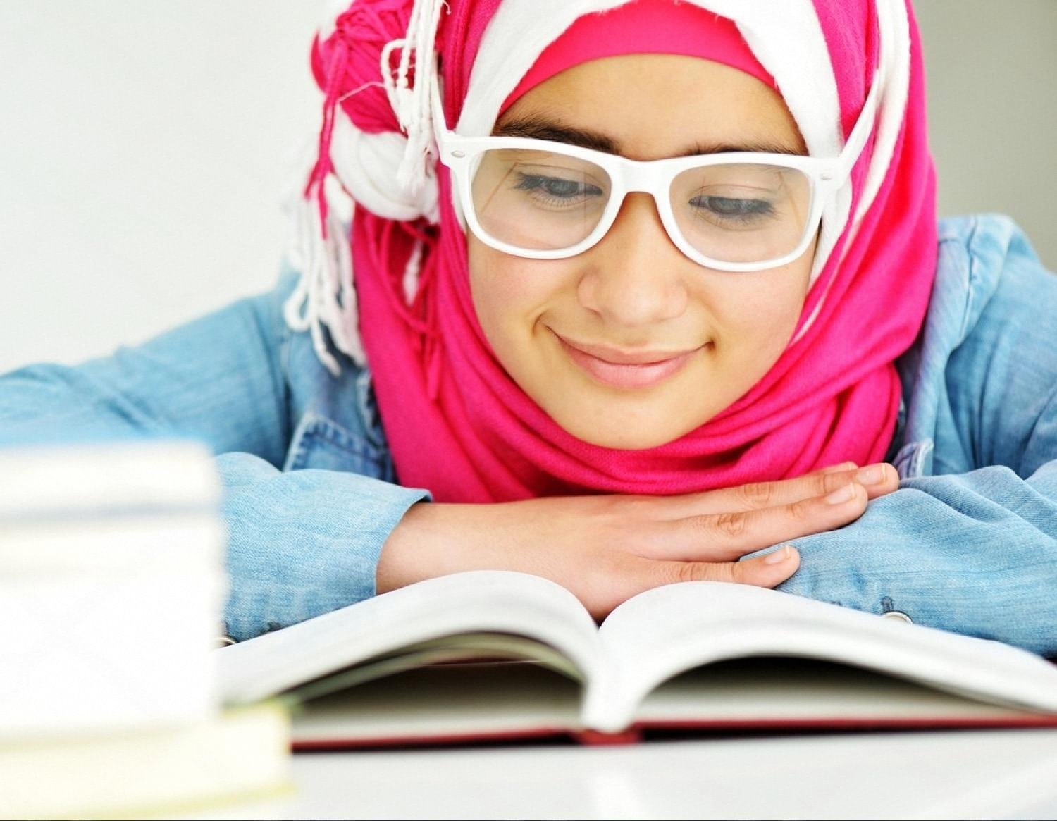 Young female student in the UAE reading a textbook while preparing for university admission